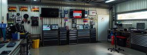 a professional automotive inspection station in burleigh heads, featuring a prominently displayed budget roadworthy certificate on the wall, illuminated by bright industrial lighting and surrounded by tools and equipment for vehicle assessments.