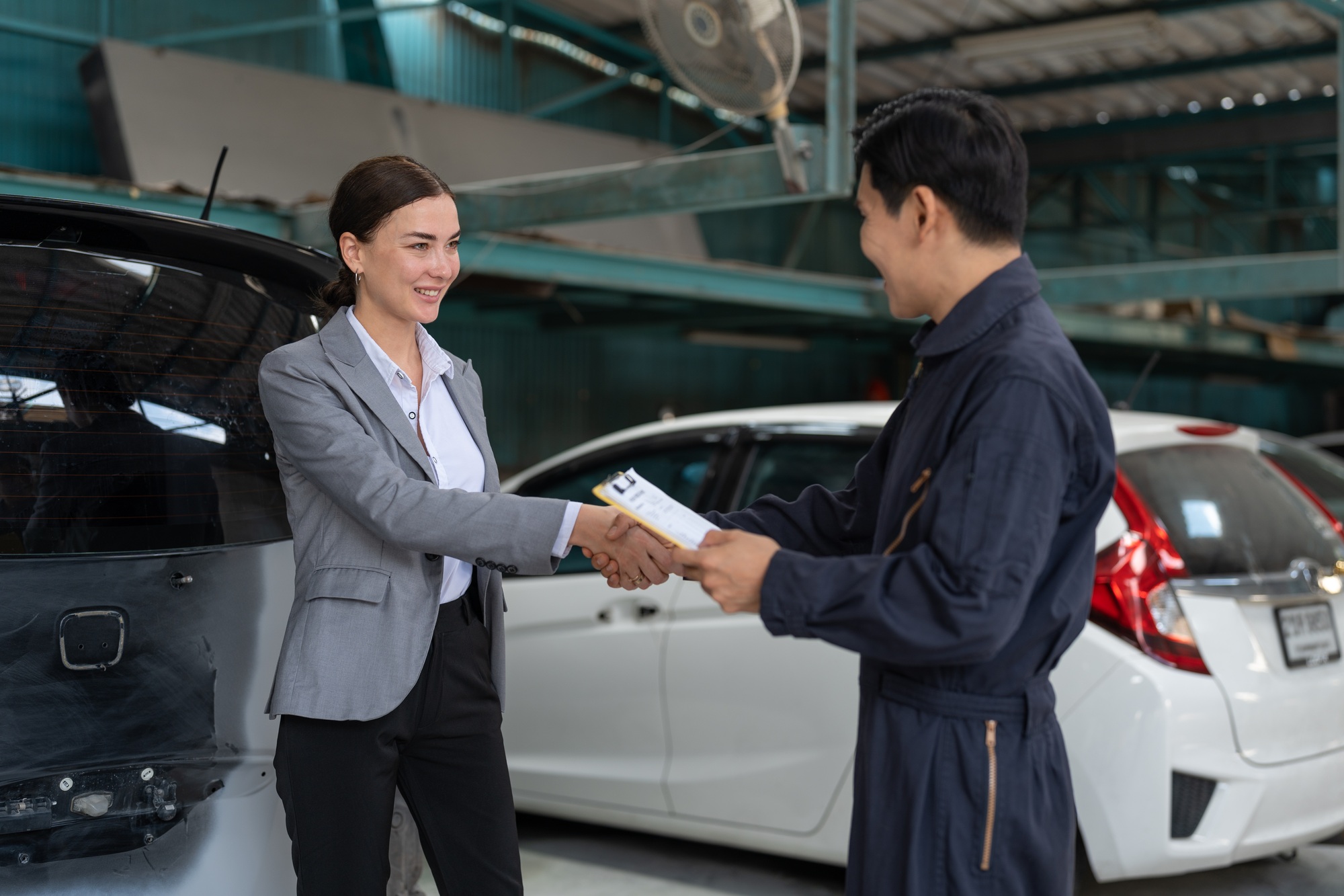 Asian car mechanic man shaking hands with woman client after finished repair car at garage service