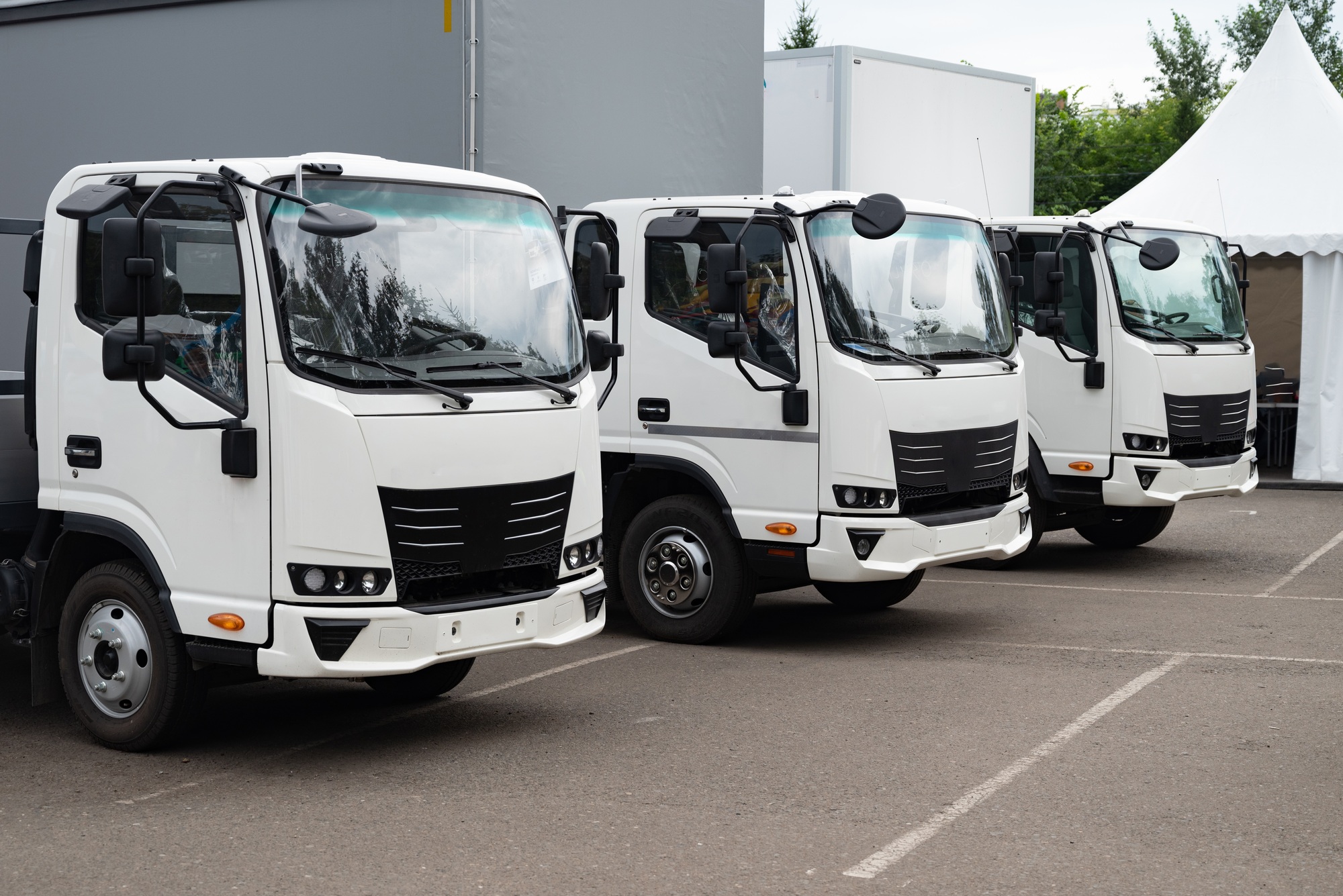 Fleet of white delivery trucks parked in a lot.