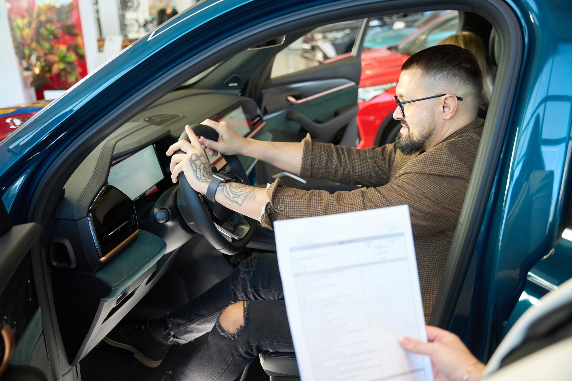 Young man evaluates the steering wheel of a new car