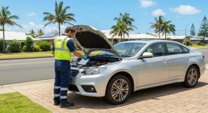 image showing a licensed mobile UBER vehicle inspector in high-visibility workwear conducting a roadworthy inspection on a well-maintained sedan or SUV. The vehicle should be parked in a sunny, suburban Gold Coast setting — such as a residential driveway or street with palm trees, coastal-style homes, and clear blue skies. The inspector may be checking tyres, examining under the bonnet, or marking items on a digital tablet. The image should feel professional, approachable, and trustworthy, appealing to everyday car owners preparing for sale or registration. No text or logos; just a clean, natural, and realistic visual.
